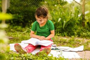 carino poco ragazza lettura libro nel parco foto