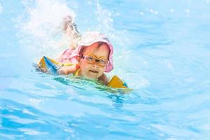 contento poco ragazza giocando con colorato gonfiabile squillare nel all'aperto nuoto piscina su caldo estate giorno. bambini imparare per nuotare. bambino acqua giocattoli. bambini giocare nel tropicale ricorrere. famiglia spiaggia vacanza. foto