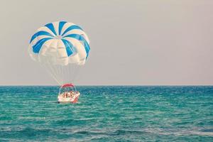 spettacolare panoramico Visualizza su il mare e blu cielo con persone volante su un' colorato paracadute rimorchiato di un' il motore barca foto