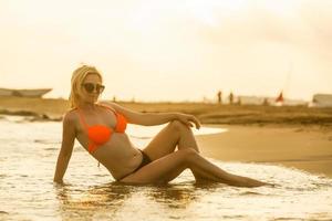 romantico sogni, bellissimo ragazza seduta solo su calma silenzioso tramonto spiaggia, rilassamento foto