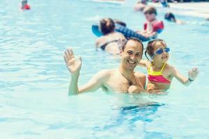 poco ragazza e contento papà avendo divertimento insieme nel all'aperto nuoto piscina foto