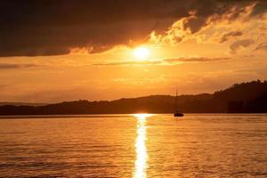 un' barca a vela su un' lago con tramonto foto