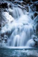 un' cascata nel inverno circondato di neve e ghiaccio foto