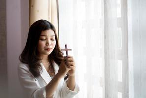 donna che tiene una croce in preghiera foto