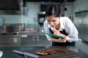 ritratto di alunno cucinando apprendista prendere Appunti su ogni passo come il capocuoco cuochi nel il culinario dell'accademia cucina. foto