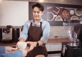 giovane barista con il Intenzione di fabbricazione su un' latte macchiato caffè per soddisfare i clienti tutti e due nel aspetto e gusto, Questo tazza di caffè è pronto per essere servito. foto