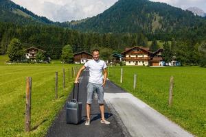 viaggiatore uomo a piedi con valigia nel il strada nel il montagne. viaggio concetto. foto