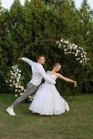 il primo danza di il sposo e sposa nel un' corto nozze vestito su un' verde prato foto
