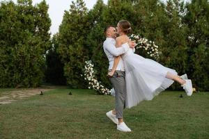 il primo danza di il sposo e sposa nel un' corto nozze vestito su un' verde prato foto