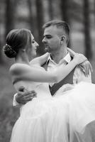 giovane coppia sposa nel un' bianca corto vestito e sposo nel un' grigio completo da uomo nel un' pino foresta foto