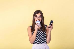 interno immagine di giovane bella vista europeo donna isolato su pesca sfondo Tenere coffe per partire e Telefono nel mano e sorridente mentre navigazione o lettura Messaggio foto