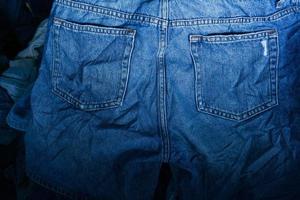 tessuto struttura, vicino su di blu denim jean struttura con indietro tasca dettaglio..distrutto strappato classico denim blu jeans cerotti, bandiera moda sfondo foto