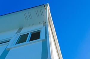 Casa tetto con pioggia grondaia di tetto superiore Casa e grande finestre su blu cielo sfondo, nuovo moderno edificio foto