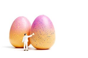 persona in miniatura pittura uova di Pasqua per il giorno di Pasqua su uno sfondo bianco