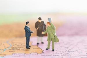 handshake di turisti in miniatura su uno sfondo di mappa del mondo, viaggio e concetto di viaggio foto