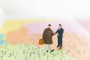 handshake di turisti in miniatura su uno sfondo di mappa del mondo, viaggio e concetto di viaggio foto