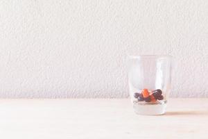 pillola in un bicchiere su un pavimento di legno e sfondo concreto foto