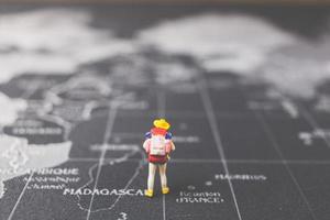 zaino in spalla in miniatura che cammina su una mappa del mondo, turismo e concetto di viaggio