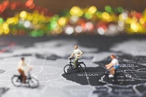 viaggiatori in miniatura in sella a una bicicletta su una mappa del mondo, viaggiando ed esplorando il concetto di mondo foto