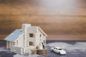sposa e sposo in miniatura con monete davanti a una casa, concetto di famiglia di successo