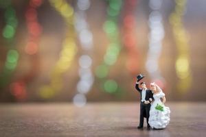 sposa e sposo in miniatura su un pavimento di legno con sfondo colorato bokeh, concetto di famiglia di successo foto