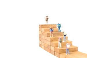Backpackers in miniatura in piedi su blocchi di legno isolati su uno sfondo bianco, concetto di viaggio foto