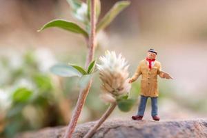 artista in miniatura che tiene un pennello e dipinge fiori in giardino foto