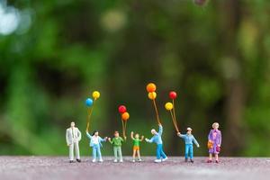 famiglia in miniatura che tiene palloncini colorati, concetto di famiglia felice foto