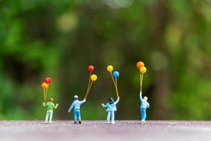 famiglia in miniatura che tiene palloncini colorati, concetto di famiglia felice
