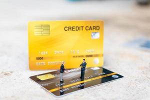 imprenditori in miniatura in piedi su una carta di credito, concetti di affari e finanza foto