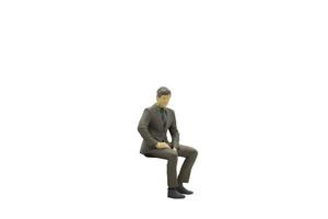 uomo d'affari in miniatura seduta isolato su uno sfondo bianco foto