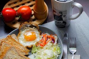 colazione, fritte uova, fritte salsiccia, verdura insalata e crostini su un' Marrone di legno tavolo con caffè. foto