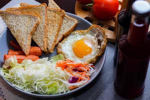 colazione, fritte uova, fritte salsiccia, verdura insalata e crostini su un' Marrone di legno tavolo con caffè. foto