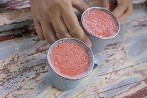 vicino su foto di fresco fragola succo su il blu tazza a il giardino negozio. il foto è adatto per uso per salutare bere, menù sfondo, e bevanda soddisfare media.