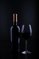 primo piano bottiglia di vino e vetro con sfondo nero foto
