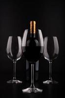 bottiglie di vino e bicchiere pieno con sfondo nero foto