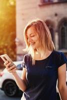 donna con bretelle utilizzando smartphone a città strada foto