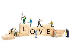 lavoratori in miniatura che costruiscono la parola amore su blocchi di legno con uno sfondo bianco, il concetto di San Valentino foto