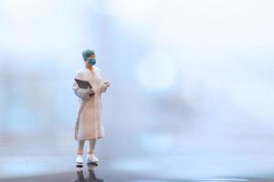medico in miniatura che indossa una maschera facciale durante il coronavirus e l'epidemia di influenza, il concetto di protezione da virus e malattie