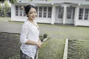 un' giovane indonesiano donna con un' contento riuscito espressione indossare un' bianca kebaya. di Kartini giorno concetto. foto