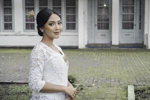 un' giovane indonesiano donna con un' contento riuscito espressione indossare un' bianca kebaya. di Kartini giorno concetto. foto