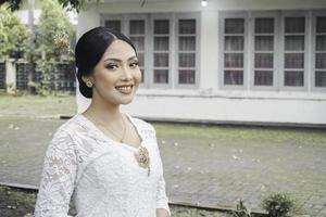 un' giovane indonesiano donna con un' contento riuscito espressione indossare un' bianca kebaya. di Kartini giorno concetto. foto