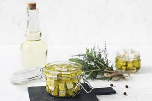 feta marinata in un barattolo di vetro, spezie e olio d'oliva aromatizzato su uno sfondo di legno
