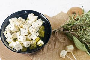 feta marinata su un piatto su una tavola di legno con spezie su uno sfondo bianco foto