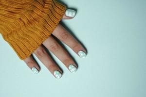 un' bellissimo femmina mano con un' colorato manicure, vestito nel un' caldo di lana color senape maglione foto