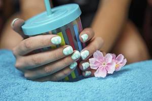 bellissimo Da donna mani con colorato manicure hold un' multicolore tazza con un' potabile tubo foto