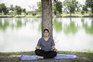 la bella donna grassa asiatica gioca a yoga al parco, ha bisogno di dimagrire il corpo foto