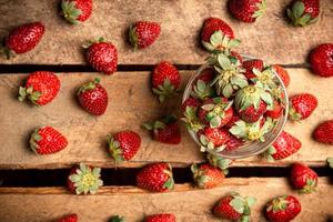 fragole in un bicchiere e su un tavolo foto