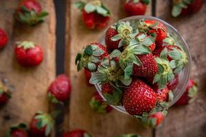 fragole in un bicchiere e su un tavolo foto