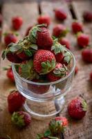 fragole in un bicchiere e su un tavolo foto